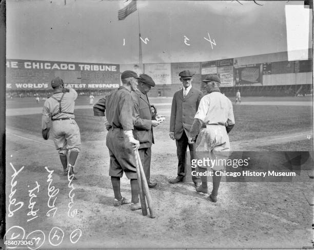 Boston Braves baseball player Evers and Chicago Cubs baseball player Leach standing with Klem and umpire Hart behind home plate on the field at West...
