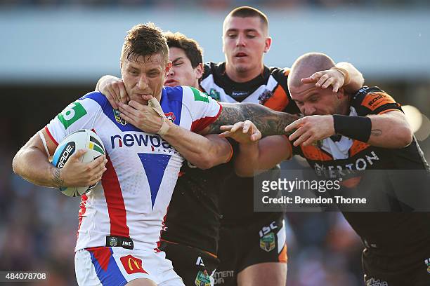 Tariq Sims of the Knights is tackled by the Tigers defence during the round 23 NRL match between the Wests Tigers and the Newcastle Knights at...