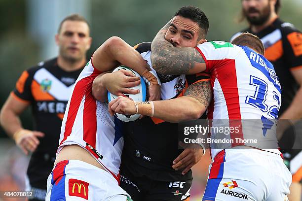 Dene Halatau of the Tigers is tackled by the Knights defence during the round 23 NRL match between the Wests Tigers and the Newcastle Knights at...