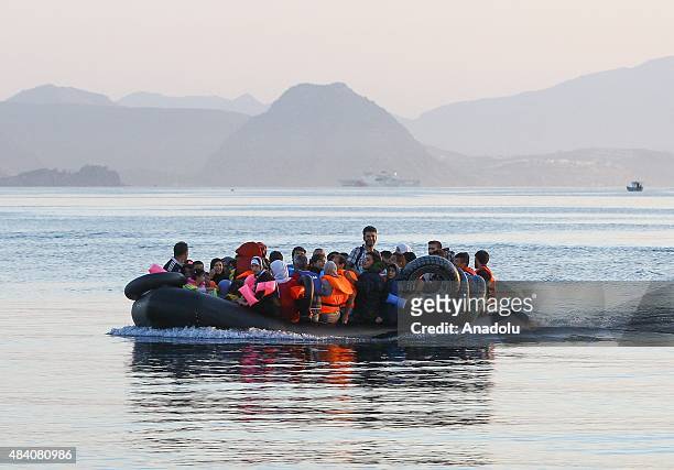 Mostly Syrian, refugees and migrants celebrate upon arrival on the Greek island of Kos after crossing a part of the Aegean Sea between Turkey and...