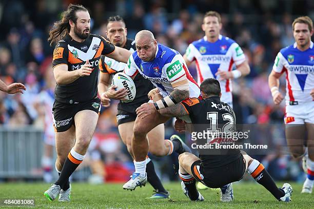Jeremy Smith of the Knights is tackled by Dene Halatau of the Tigers during the round 23 NRL match between the Wests Tigers and the Newcastle Knights...