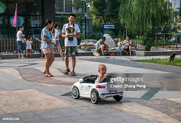 Two-year old boy sit on an electric toy car which is remote-controlled by his parent following behind. China is considering whether to allow all...