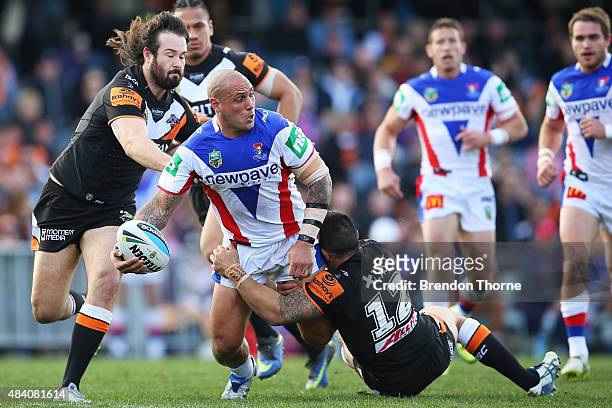 Jeremy Smith of the Knights is tackled by Dene Halatau of the Tigers during the round 23 NRL match between the Wests Tigers and the Newcastle Knights...