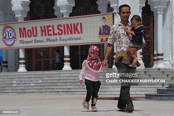 An Acehnese man and two children depart after a ceremony marking the 10th anniversary of the Helsinki peace agreement between the Free Aceh Movement...