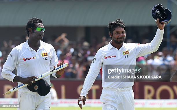 Sri Lankan cricketer Kumar Sangakkara gestures as Sri Lankan cricket captain Angelo Mathews looks on after victory on the fourth day of the opening...