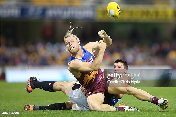 Daniel Rich of the Lions handballs while tackled by Matthew Kreuzer of the Blues during the round 20 AFL match between the Brisbane Lions and the...