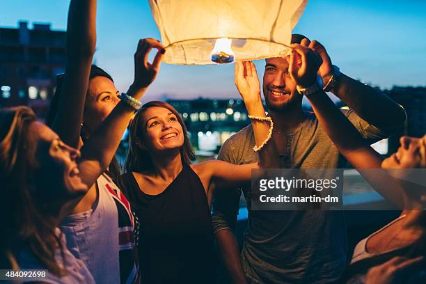freunde löst papierlaterne für silvester - summer party lights stock-fotos und bilder