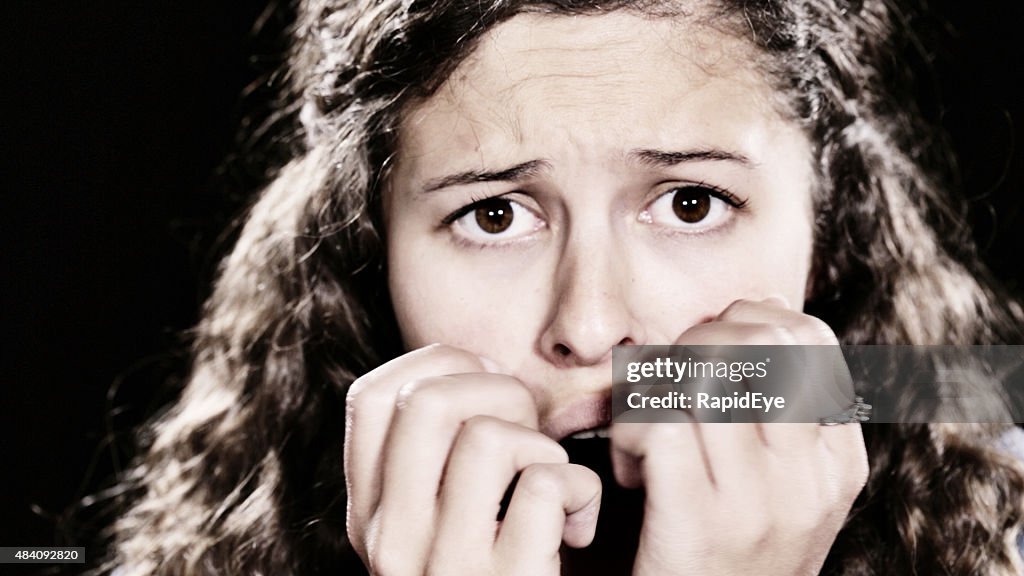 Beautiful brown-eyed young woman with hands over mouth looks anxious