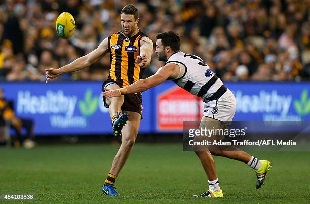 James Frawley of the Hawks kicks the ball ahead of Jimmy Bartel of the Cats during the 2015 AFL round 20 match between the Geelong Cats and the...