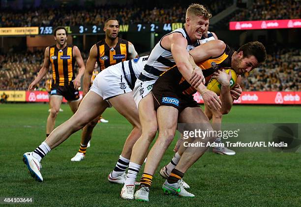 Matthew Suckling of the Hawks is tackled by Josh Caddy of the Cats during the 2015 AFL round 20 match between the Geelong Cats and the Hawthorn Hawks...