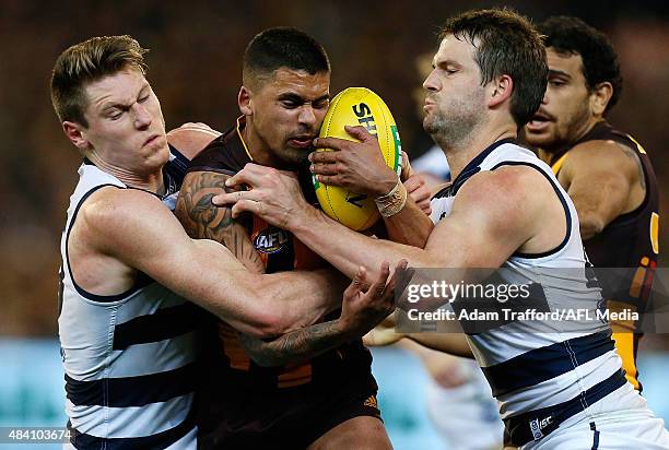 Bradley Hill of the Hawks is tackled by Mark Blicavs and Jared Rivers of the Cats during the 2015 AFL round 20 match between the Geelong Cats and the...