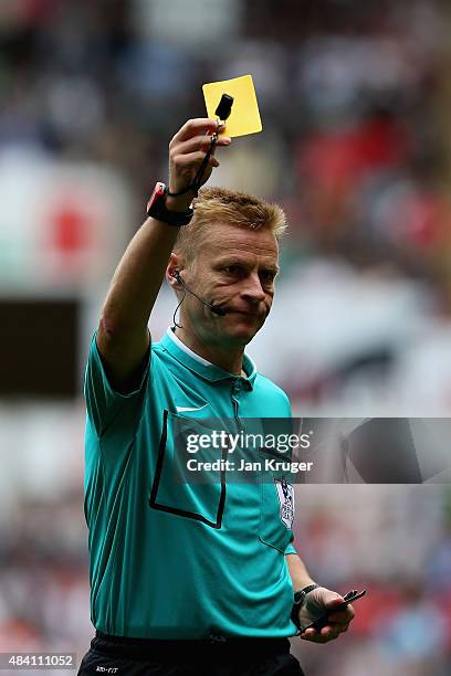 Referee Mike Jones issues a yellow card during the Barclays Premier League match between Swansea City and Newcastle United at Liberty Stadium on...