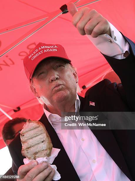 Republican presidential candidate Donald Trump eats a pork chop on a stick and gives a thumbs up sign to fairgoers at the Iowa State Fair on August...