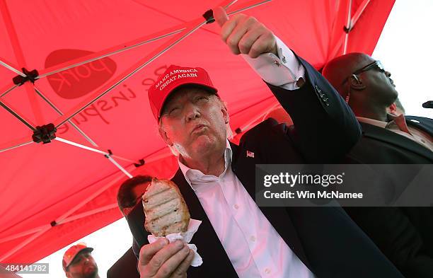 Republican presidential candidate Donald Trump eats a pork chop on a stick and gives a thumbs up sign to fairgoers while campaigning at the Iowa...