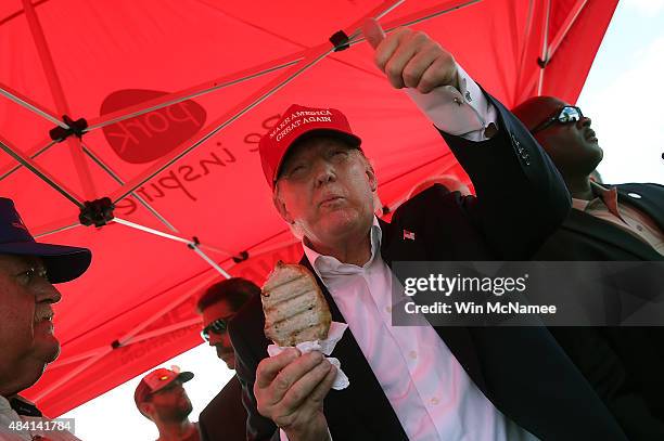 Republican presidential candidate Donald Trump eats a pork chop on a stick and gives a thumbs up sign to fairgoers while campaigning at the Iowa...