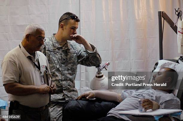 Staff photo by Shawn Patrick Ouellette: -- SPC James Elliott a medic from Bangor speaks with Hussny Hussain an Iraqi Policeman who was being treated...