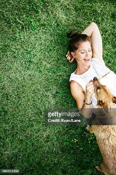 adult woman enjoying time with pet dog - lying down stockfoto's en -beelden