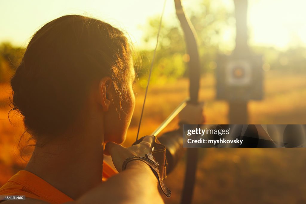 Weibliche archer im Feld bei Sonnenuntergang