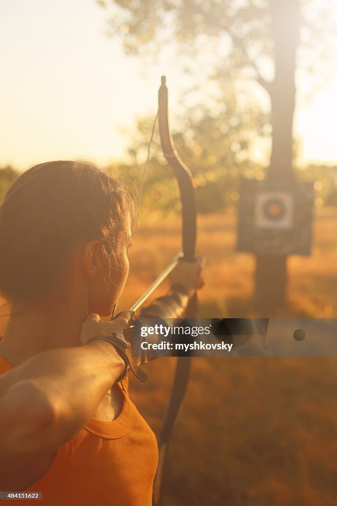Weibliche archer im Feld bei Sonnenuntergang