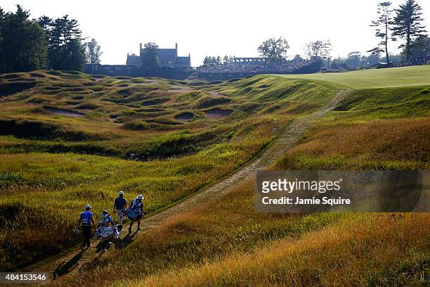 Martin Kaymer of Germany and Branden Grace of South Africa walk with their caddies up the 18th hole during the third round of the 2015 PGA...
