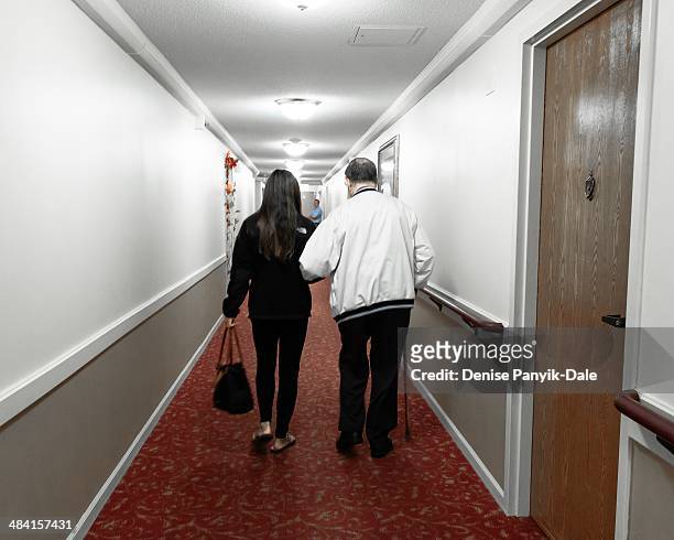 Granddaughter walking with grandfather in assisted living hallway