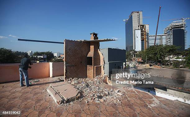 Teen flies a kite on the rooftop of a partially demolished home in the Vila Autodromo 'favela' community, with a chimney remaining and Olympic Park...