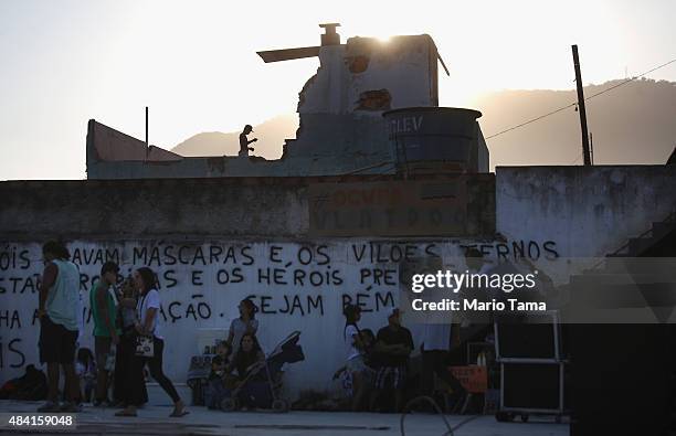 Teen prepares to fly a kite on the rooftop of a partially demolished home in the Vila Autodromo 'favela' community, with a group of protesters gather...