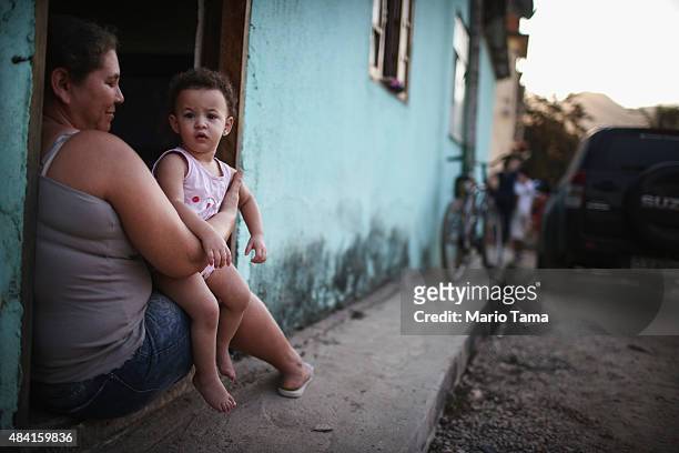 Holdout Suelady Cipriano sits with her daughter Maria in their doorway in the Vila Autodromo 'favela' community on August 15, 2015 in the Barra da...