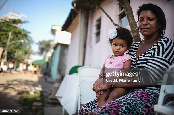 Holdout Marcia da Silva sits with her daughter Marilice in their doorway in the Vila Autodromo 'favela' community on August 15, 2015 in the Barra da...