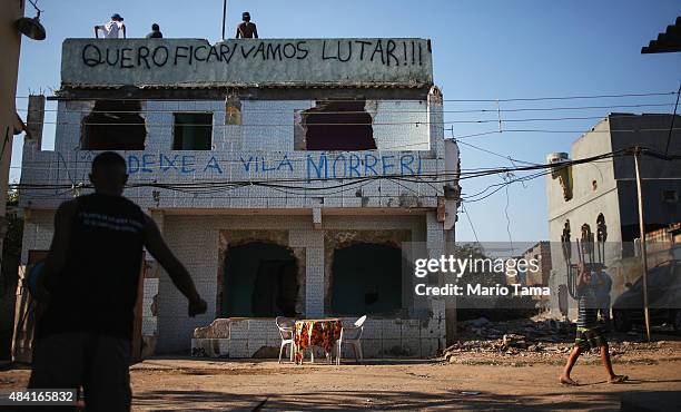 Teens stand on the rooftop of a partially demolished home in the Vila Autodromo 'favela' community on August 15, 2015 in the Barra da Tijuca...