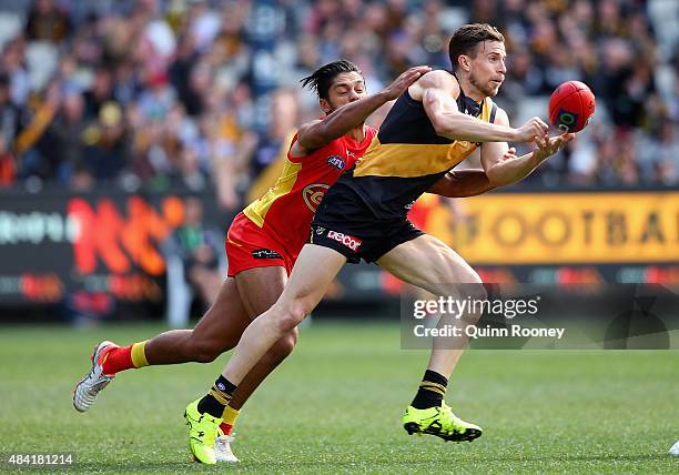 Brett Deledio of the Tigers handballs whilst being tackled by Aaron Hall of the Suns during the round 20 AFL match between the Richmond Tigers and...