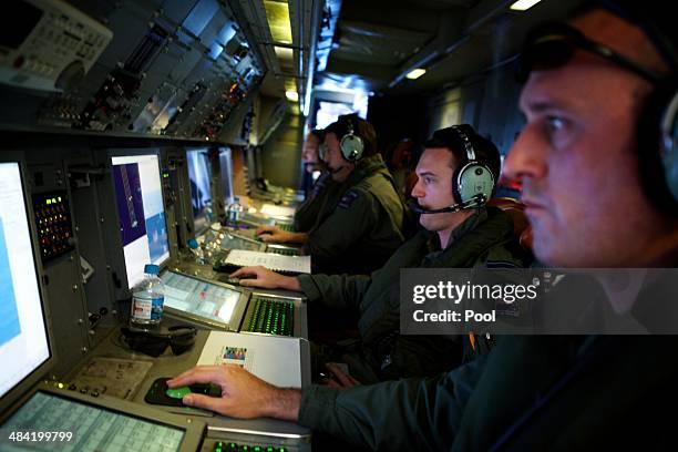 Crew members of a Royal New Zealand Air Force P-3 Orion operate radar and sensor systems during the search to locate missing Malaysia Airways Flight...