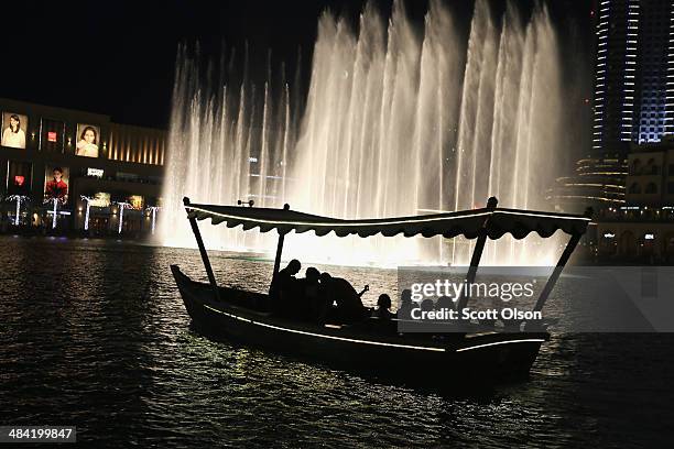 Visitors watch the water show in the Dubai Fountain from a tour boat on April 9, 2014 in Dubai, United Arab Emirates. The Dubai Fountain is the...