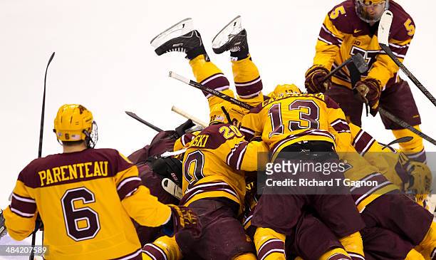The legs of Tom Serratore of the Minnesota Golden Gophers are in the air as his teammates Taylor Cammarata, Jake Parenteau, Michael Brodzinski and...