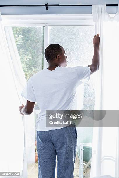 african american man opening curtains on sunny morning - open day 9 bildbanksfoton och bilder