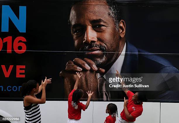 Kids pose for a photo in front of the campaign bus of republican presidential hopeful Ben Carson after church services at Maple Street Missionary...