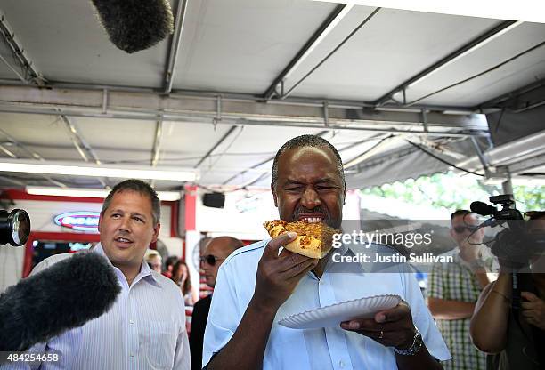 Republican presidential hopeful Ben Carson eats a piece of pizza while touring the Iowa State Fair on August 16, 2015 in Des Moines, Iowa....