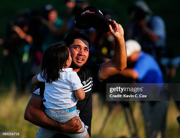 Jason Day of Australia walks off the 18th green with his son Dash after winning the 2015 PGA Championship with a score of 20-under par at Whistling...