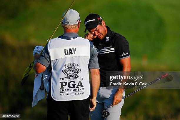 Jason Day of Australia celebrates with his caddie Colin Swatton on the 18th green after winning the 2015 PGA Championship with a score of 20-under...