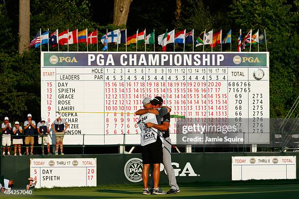 Jason Day of Australia hugs his caddie Colin Swatton on the 18th green after winning the 2015 PGA Championship with a score of 20-under par at...