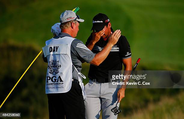 Jason Day of Australia celebrates with his caddie Colin Swatton on the 18th green after winning the 2015 PGA Championship with a score of 20-under...
