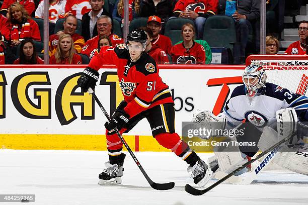 Kenny Agostino of the Calgary Flames looks to tip the puck past Michael Hutchinson of the Winnipeg Jets at Scotiabank Saddledome on April 11, 2014 in...