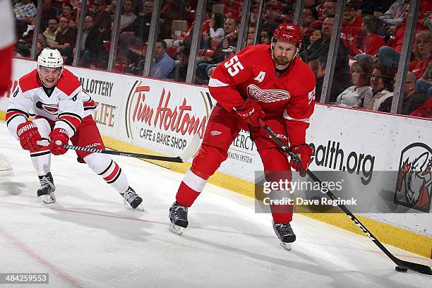 Niklas Kronwall of the Detroit Red Wings handles the puck as Andrei Loktionov of the Carolina Hurricanes pressures him during an NHL game on April...