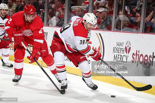 Patrick Dwyer of the Carolina Hurricanes skates with the puck as Brendan Smith of the Detroit Red Wings defends him during an NHL game on April 11,...