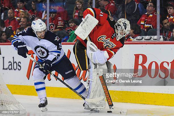 Karri Ramo of the Calgary Flames tries to pass the puck up as Jim Slater of the Winnipeg Jets attempts to check him during an NHL game at Scotiabank...