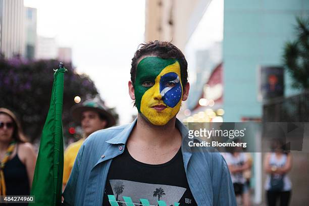 Demonstrator with the Brazilian flag painted on his face marches during a protest in Sao Paulo, Brazil, on Sunday, Aug. 16, 2015. Nationwide street...