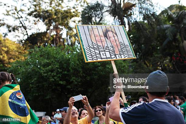 Demonstrator holds a placard with a photo of Brazilian President Dilma Rousseff, right, and former Brazilian President Luiz Inacio Lula da Silva...