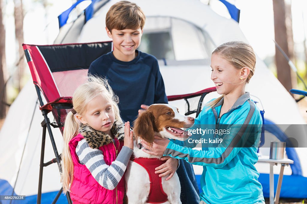 Tres niños en el campamento viaje de la familia interactivo perro