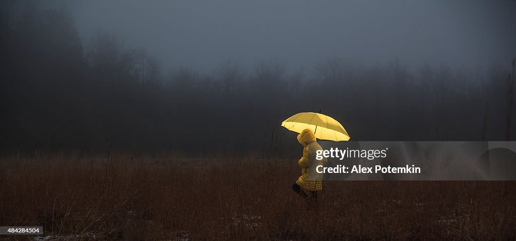 Little girl crossing the field in fog