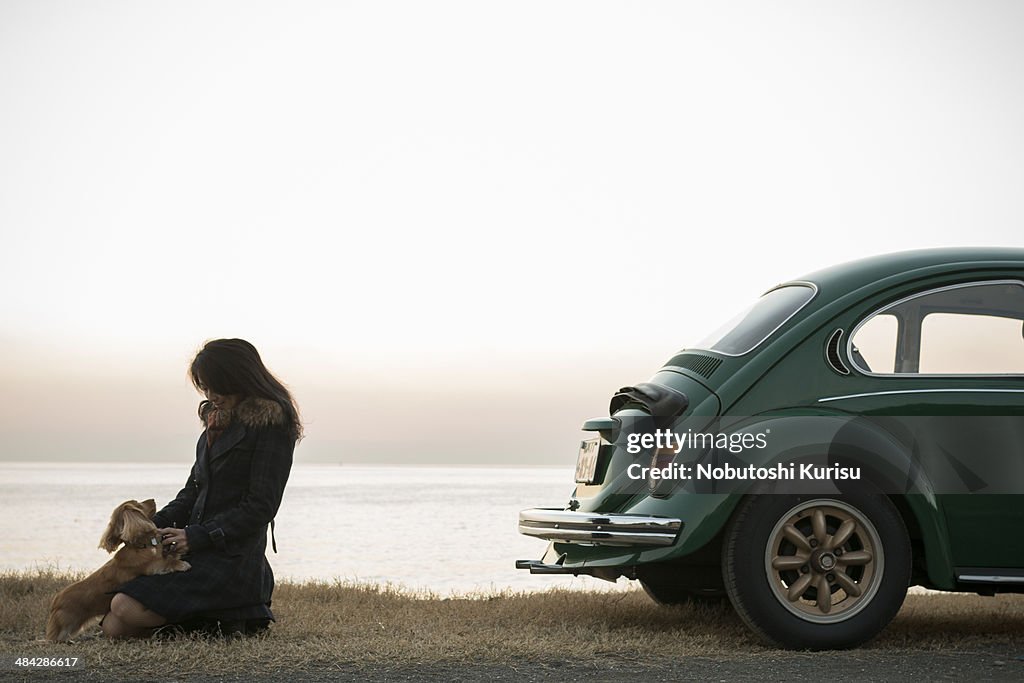 A woman and a dog are standing near the car